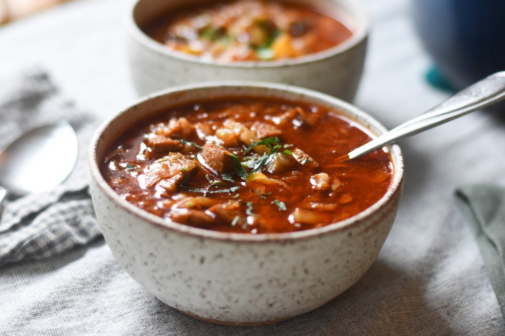 Kapustnica soup, bright red soup with chunks of potatoes and pork