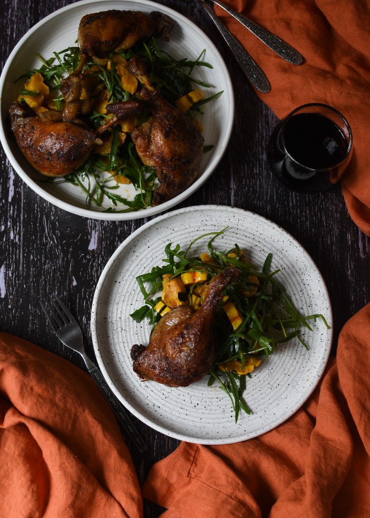 Platter of duck confit with delicata squash and arugula. Autumn meal. Next to a plate of the same. Gluten free. Sunday meal.
