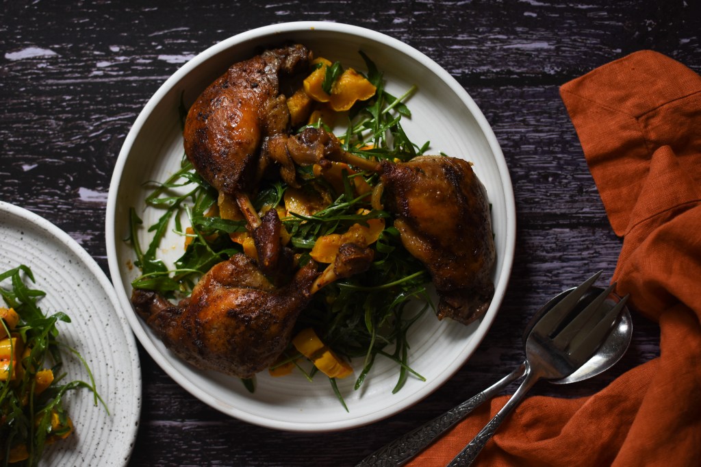 Platter of duck confit. It is next to orange linen and ready to be served. Celebratory meal. 